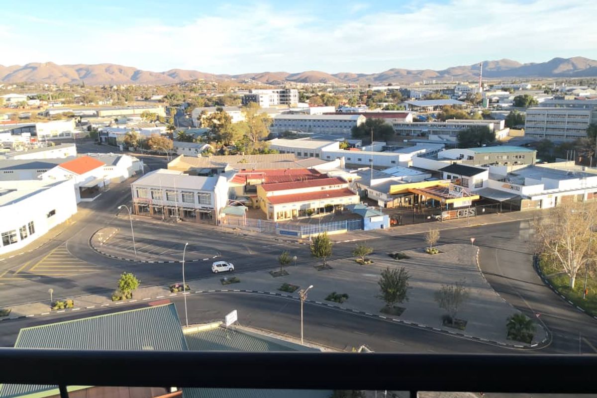 Elevated panoramic view overlooking the surrounding urban landscape, commercial buildings, and distant mountain ranges.