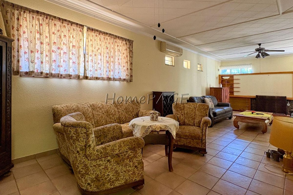 Spacious living area featuring tiled flooring, a ceiling fan, and wall-mounted air conditioning unit.