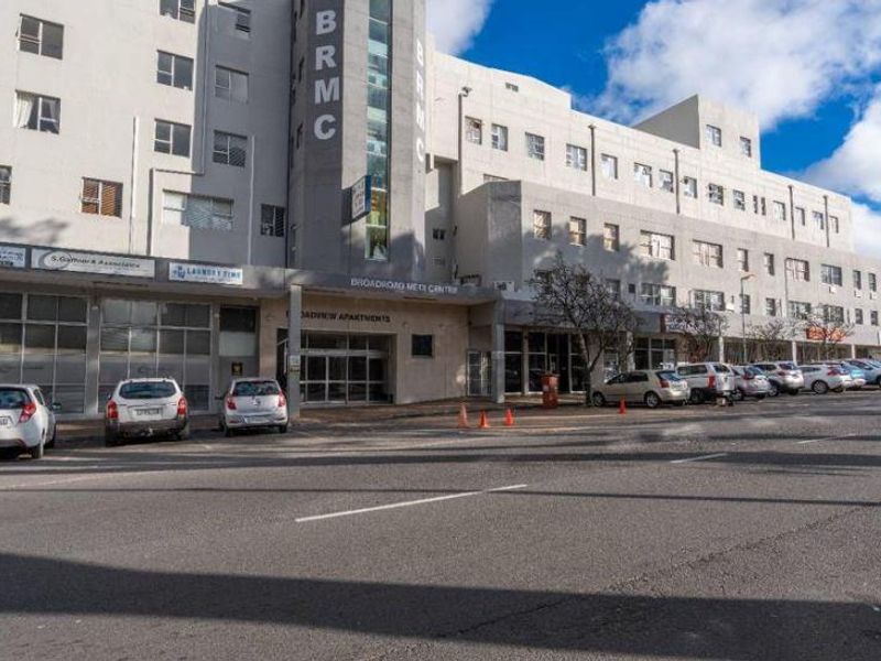 Exterior view of the Broadroad Medix Center featuring a multi-story commercial building with ground-level storefronts and an adjacent parking area.