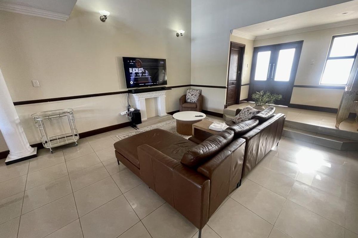 Spacious living area featuring high ceilings, tiled flooring, decorative wall molding, and a built-in fireplace mantle.