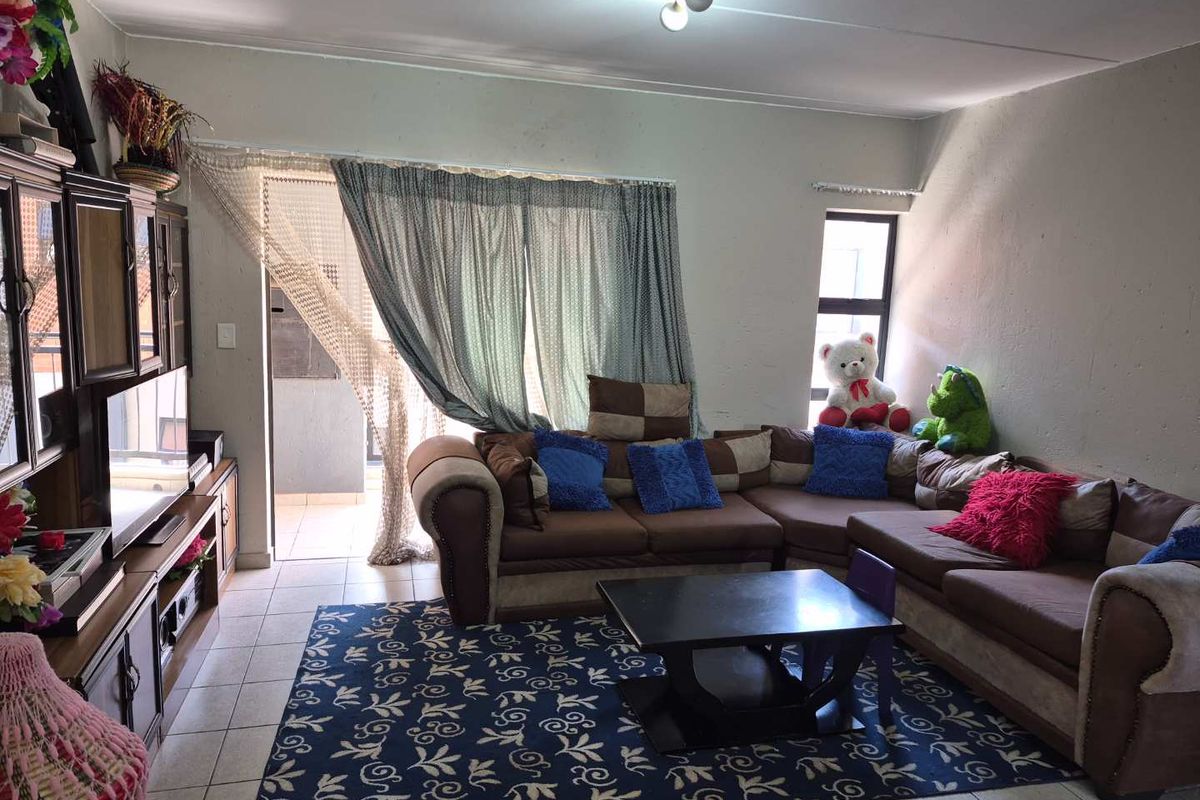 A living room featuring tiled flooring and a sliding glass door providing access to an outdoor area.