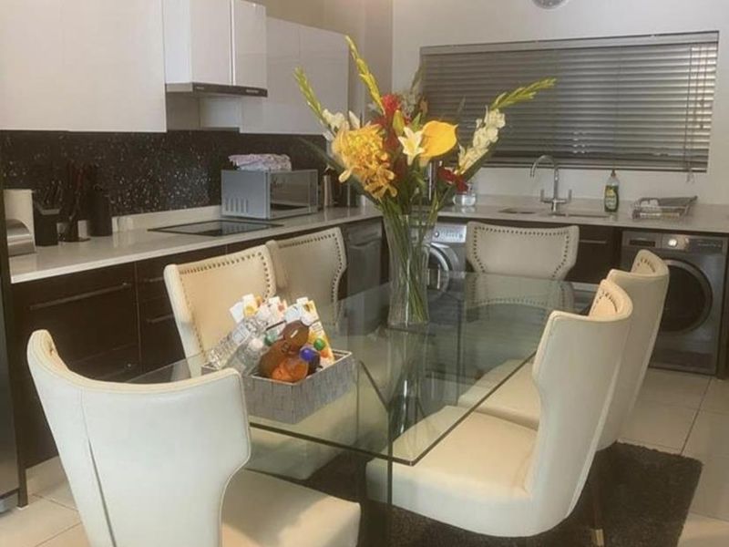 Open plan kitchen and dining area featuring modern cabinetry, stone countertops, integrated appliances, and tiled flooring with a functional layout.