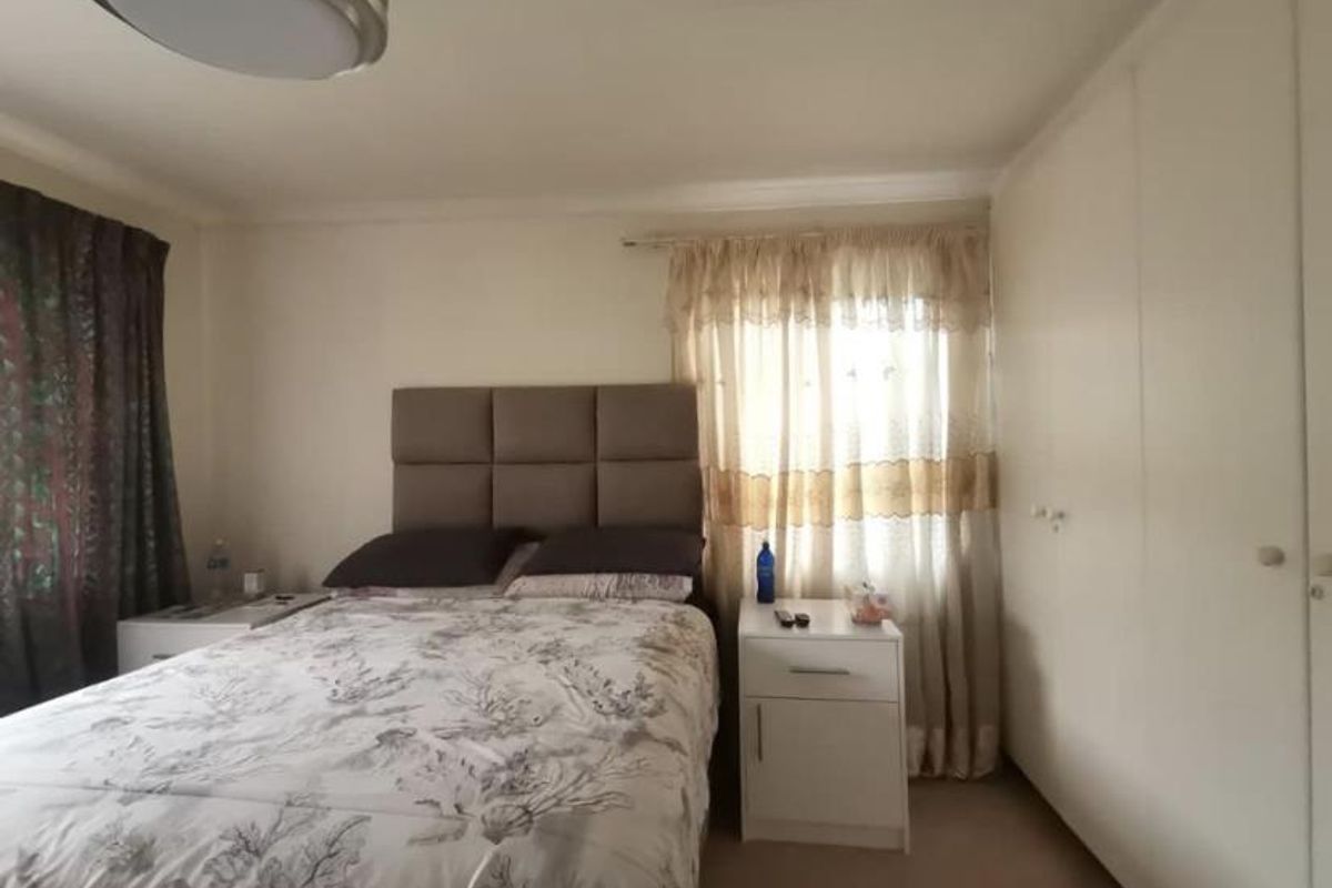A bedroom featuring built-in cupboards and a window with curtain tracks.