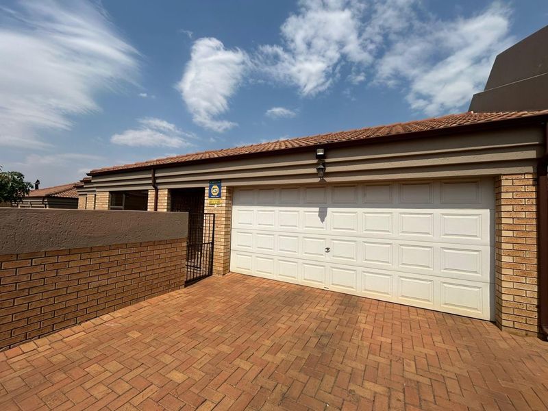 Front exterior view of the cluster property featuring a paved driveway, facebrick facade, and a secure single garage.