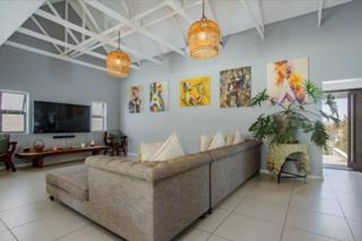 Spacious living room featuring high vaulted ceilings with exposed trusses, tiled flooring, and large windows providing ample natural light.