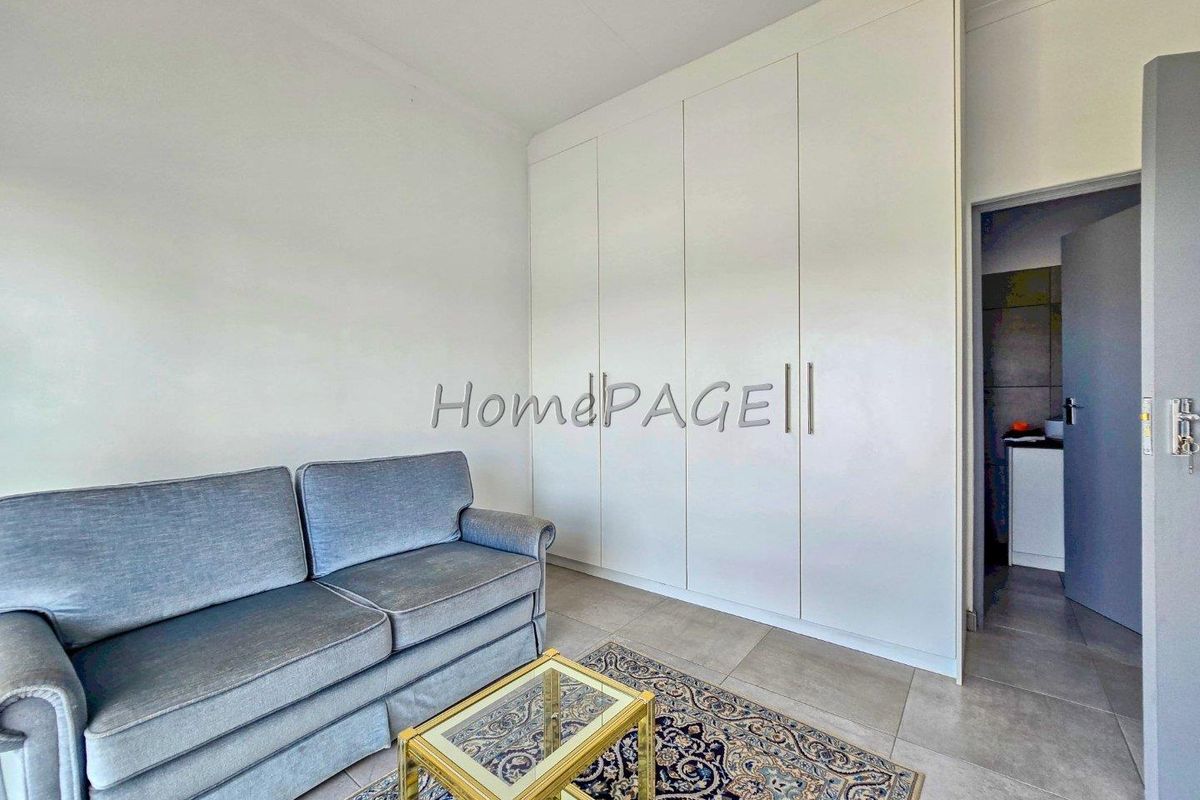 A bedroom featuring built-in floor-to-ceiling wardrobes and tiled flooring, with an adjacent doorway leading to an en-suite bathroom.