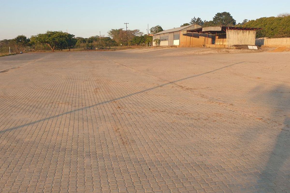 Expansive paved yard area on a small holding, featuring a large industrial-style shed structure in the background.
