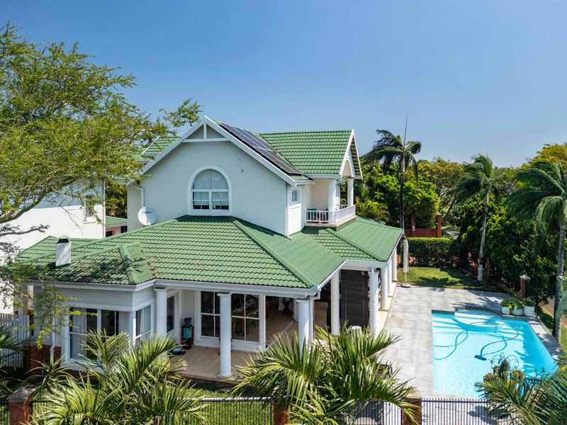 Aerial view of the rear exterior featuring a swimming pool, covered patio, balcony, and a well-maintained tiled roof with solar panels.