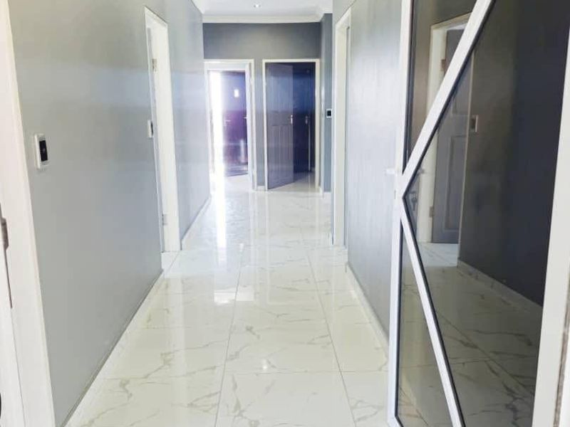 A bright, modern hallway featuring polished marble-look floor tiles, recessed downlighting, and contemporary internal doors, creating a clean and spacious transition area.