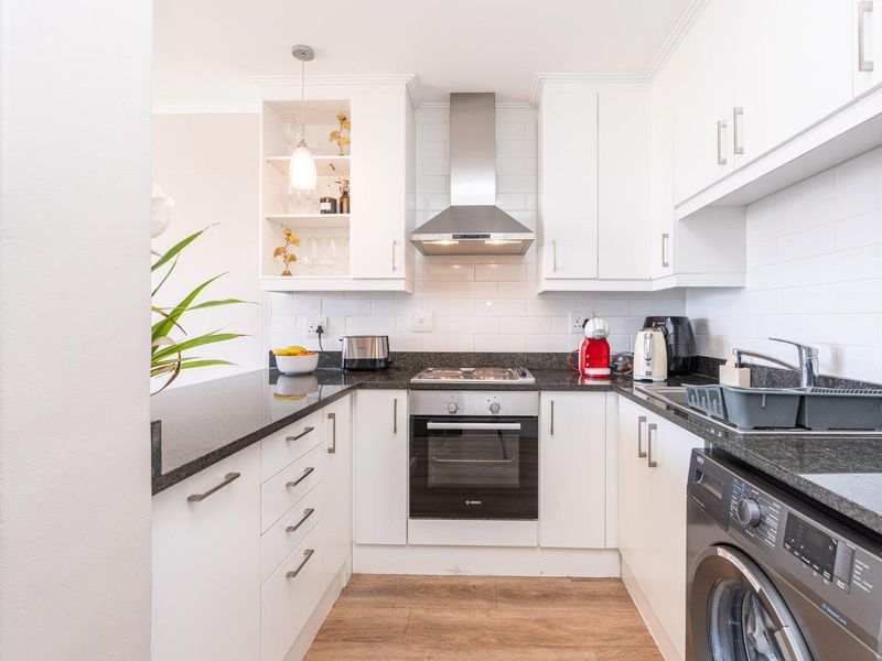 Modern kitchen featuring white cabinetry, granite countertops, subway tile backsplash, and integrated stainless steel appliances, offering a clean and functional workspace.