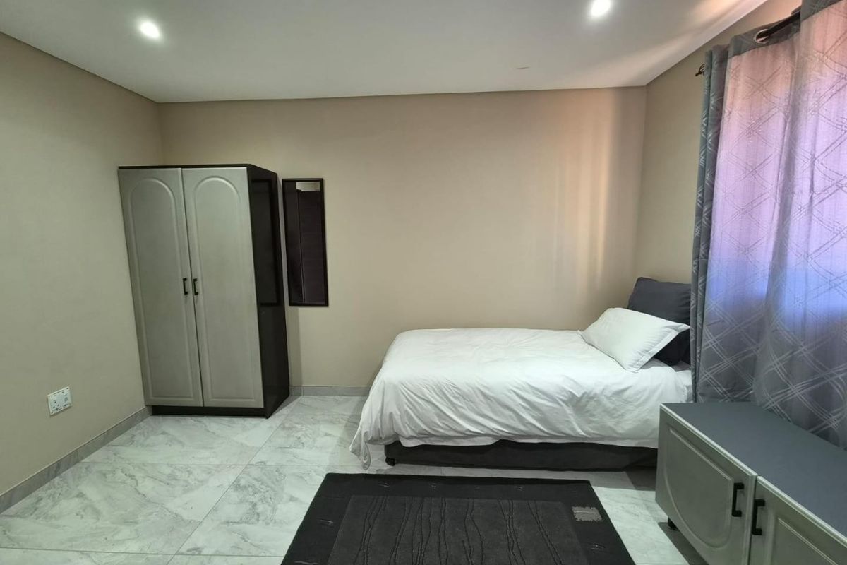 A bedroom featuring marble-look floor tiles, recessed downlighting, and neutral wall finishes, providing a clean and functional living space.