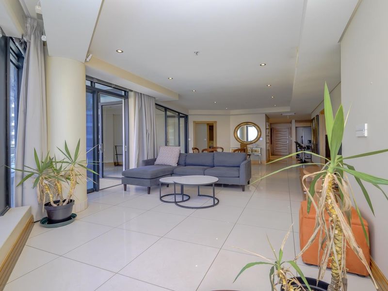 Spacious open-plan living area featuring large sliding glass doors, neutral tiled flooring, and recessed downlighting, offering a bright and airy atmosphere.