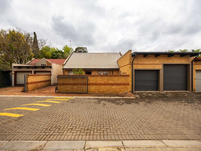 Front elevation of a brick-built house featuring multiple roller garage doors, a secure gated entrance, and a paved driveway area.