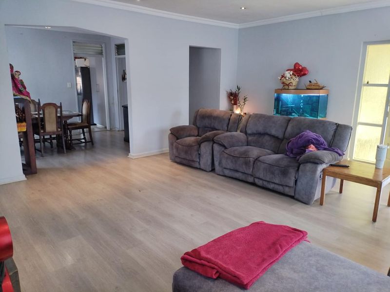 Spacious open-plan living area featuring light-toned laminate flooring, recessed downlighting, and neutral wall finishes, providing a versatile layout for dining and relaxation.