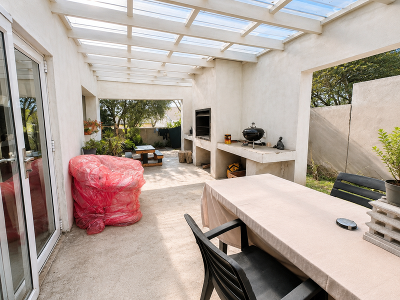 Covered patio area featuring a built-in braai, concrete prep surface, and translucent roof panels, providing a functional outdoor entertainment space.
