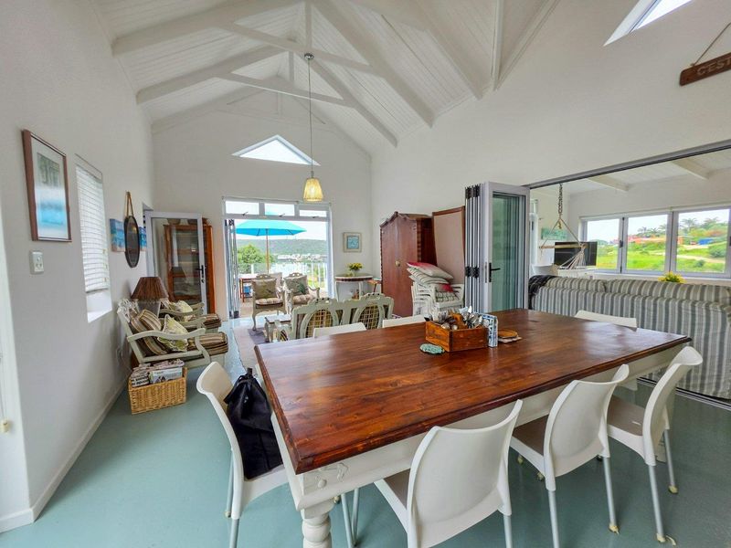 Spacious open-plan living and dining area featuring a high vaulted ceiling with exposed beams, large bi-fold doors, and abundant natural light.