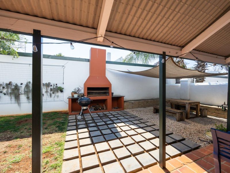 Covered outdoor patio area featuring a built-in braai, paved flooring, and a gravel section, ideal for outdoor entertaining and relaxation.