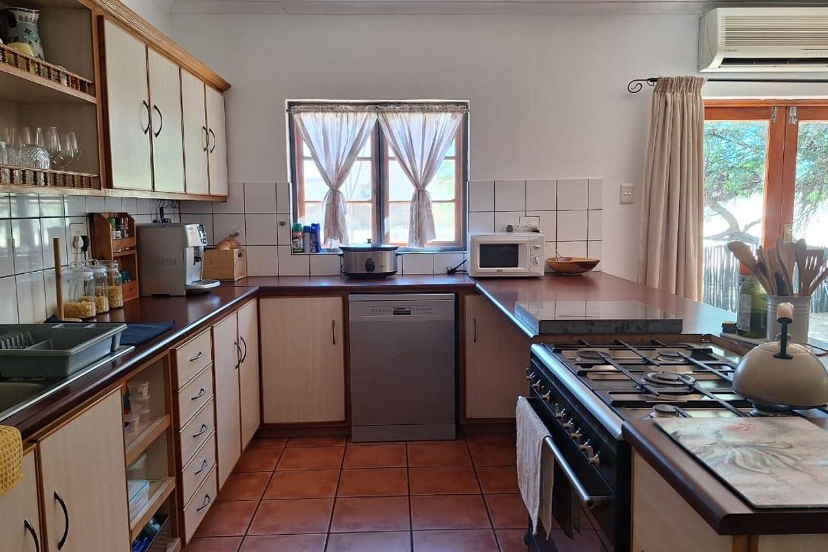 A functional kitchen featuring wooden cabinetry, tiled splashbacks, a gas hob, and a built-in oven, with direct access to the outdoor area.