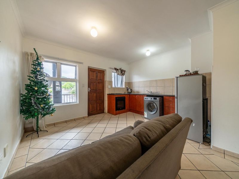 Open-plan living area featuring tiled flooring, built-in kitchen cabinetry with integrated oven, and neutral wall finishes.