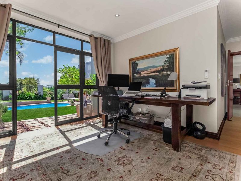 A bright home office featuring large glass sliding doors that provide direct access to the garden and pool area.