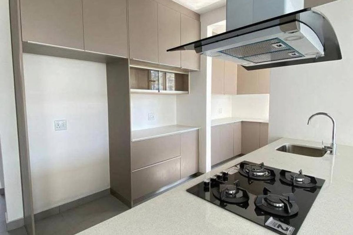 Modern kitchen featuring sleek taupe cabinetry, stone countertops, a central island with a gas hob, and a contemporary extractor fan.