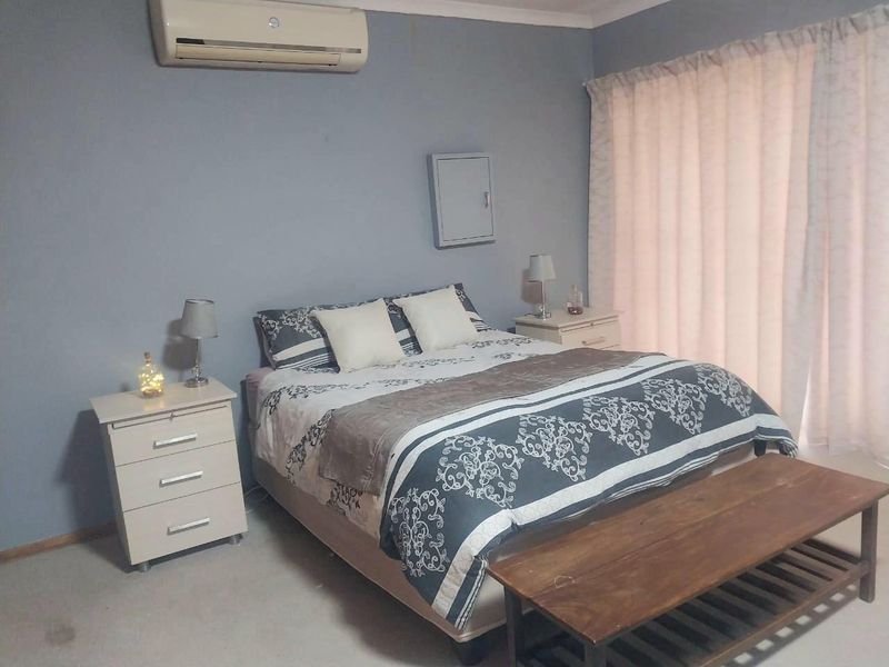 A bedroom featuring a wall-mounted split-system air conditioner and a central electrical distribution board cover.