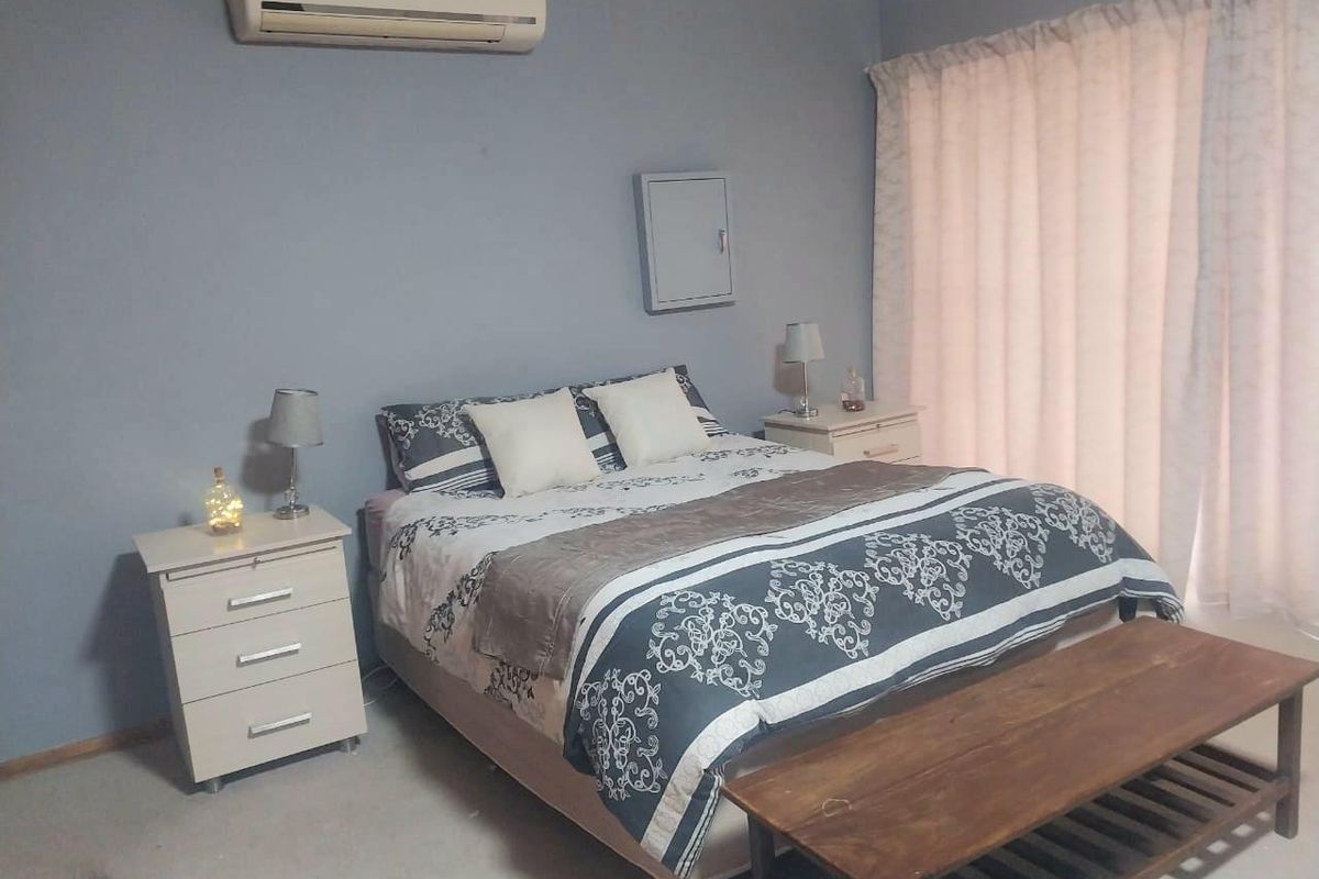 A bedroom featuring a wall-mounted split-system air conditioner and a central electrical distribution board cover.