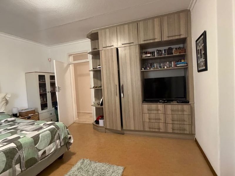 A bedroom featuring a large built-in wardrobe unit with integrated shelving and drawers, coved ceilings, and neutral wall finishes.