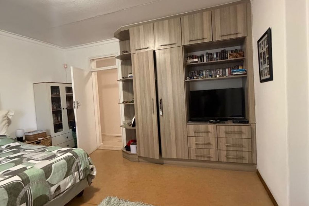 A bedroom featuring a large built-in wardrobe unit with integrated shelving and drawers, coved ceilings, and neutral wall finishes.