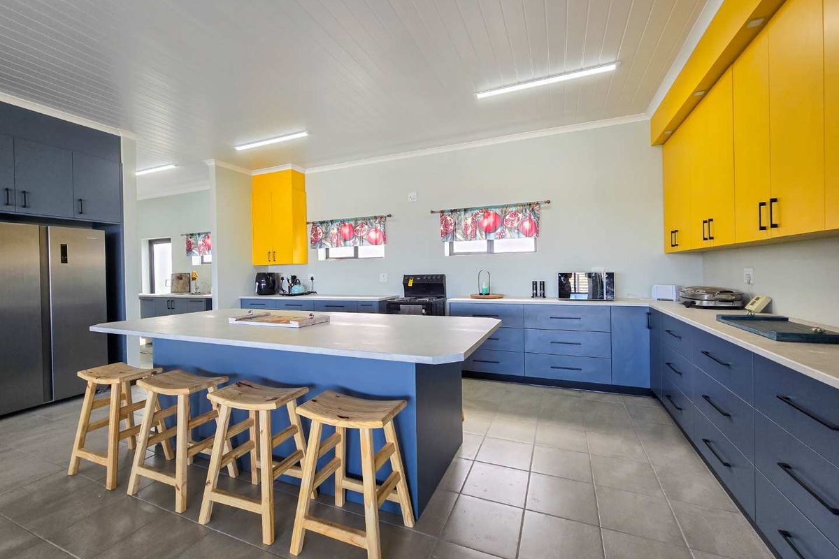 Spacious kitchen featuring a large central island, blue cabinetry, yellow overhead cupboards, tiled flooring, and integrated appliance space.