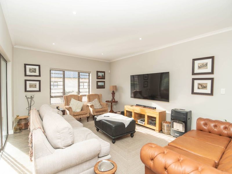 A well-lit living room featuring recessed downlights, neutral wall finishes, carpeted flooring, and large sliding glass doors providing access to the outdoor area.