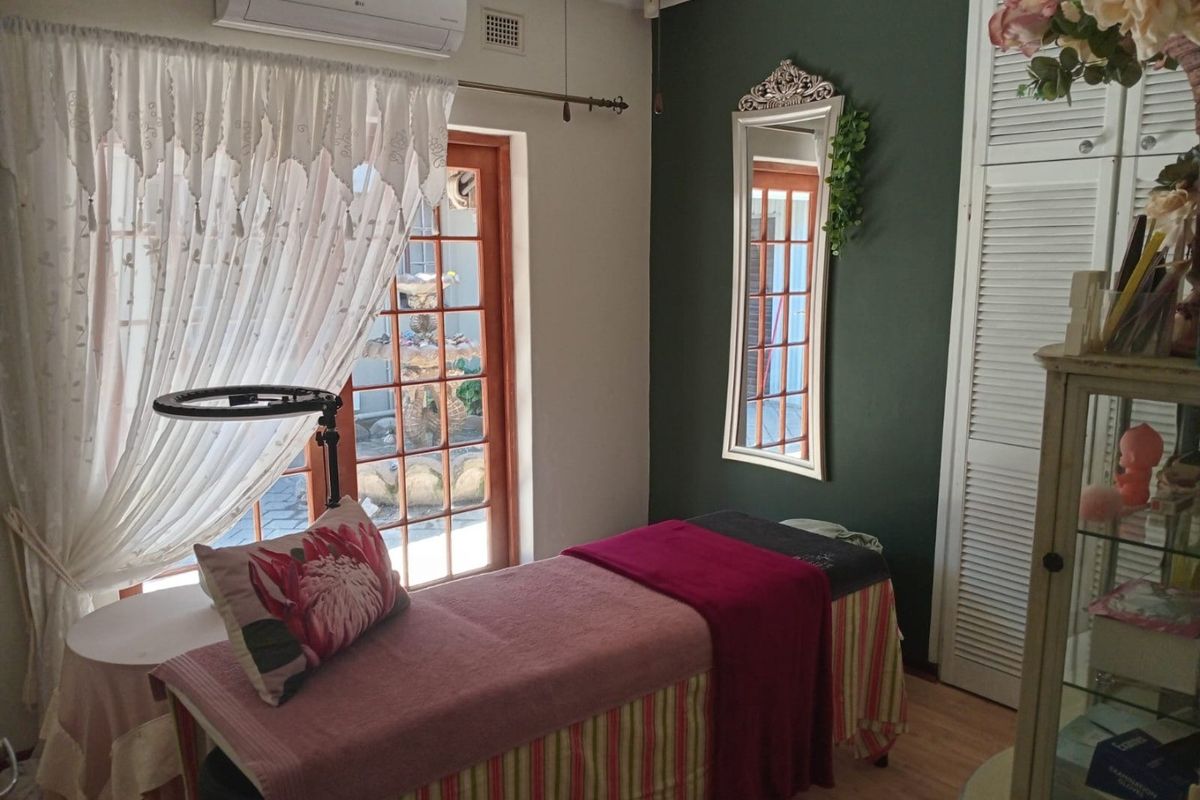 A functional bedroom space featuring laminate flooring, louvered closet doors, and a split-system air conditioner, with direct access to an outdoor area.