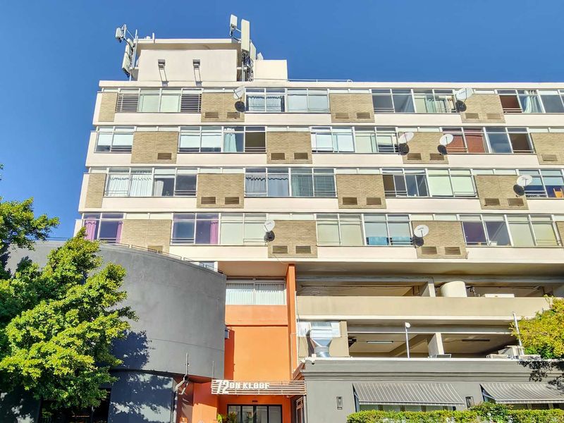 A multi-story apartment building facade featuring brick cladding, aluminum windows, and ground-level commercial access.