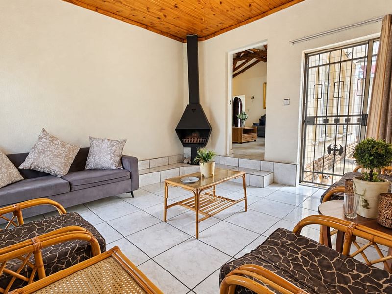 Living room featuring a freestanding fireplace, tiled flooring, and a timber ceiling, with direct access to an outdoor area through a security gate.