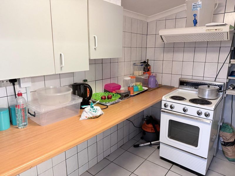 A functional kitchen featuring tiled walls, laminate countertops, and a freestanding electric stove with an overhead extractor fan.