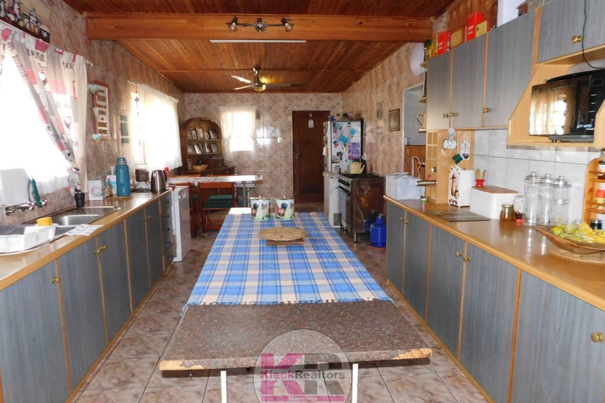 Spacious kitchen featuring extensive built-in cabinetry, tiled flooring, and a timber ceiling, offering a functional layout with ample storage space.