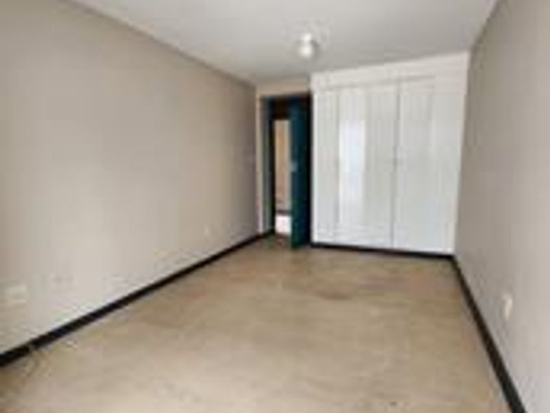 An empty bedroom featuring tiled flooring, built-in cupboards, and neutral wall finishes, ready for personalization.