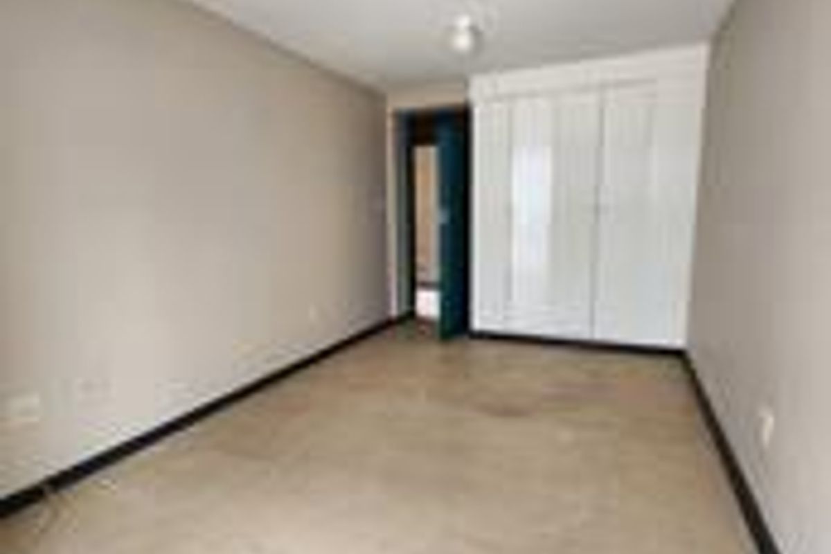 An empty bedroom featuring tiled flooring, built-in cupboards, and neutral wall finishes, ready for personalization.