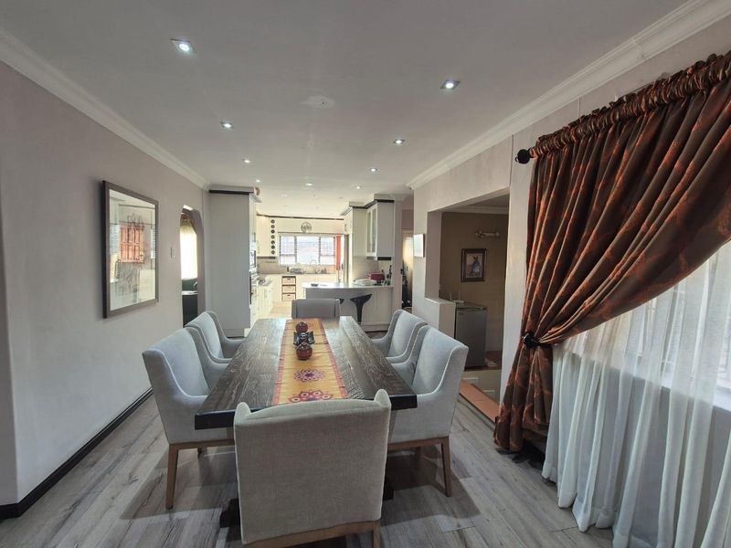 Spacious open-plan dining area featuring modern laminate flooring, recessed lighting, and a seamless transition into the adjacent kitchen space.