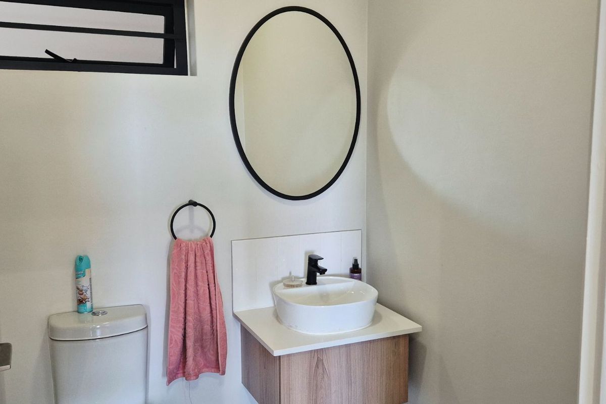 A modern bathroom featuring a vanity cabinet with a vessel sink, black fixtures, and an oval mirror.