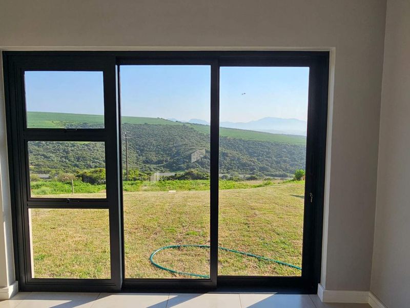 Bright living area featuring large sliding glass doors that provide expansive views of the surrounding landscape and natural light.