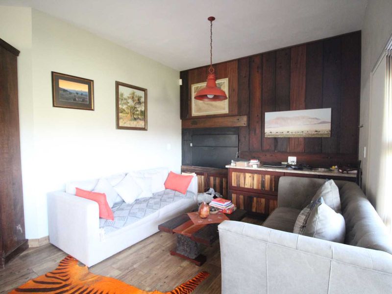 A cozy living room featuring a built-in fireplace, rustic timber wall paneling, and warm pendant lighting, creating a comfortable and inviting atmosphere.