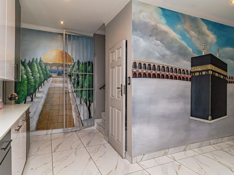 A modern kitchen area featuring high-gloss cabinetry, stone countertops, and marble-look tiled flooring, accented by large-scale wall murals.