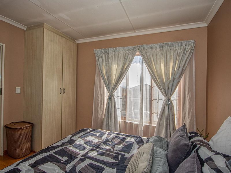 A cozy bedroom featuring built-in wooden cabinetry and a window with natural light, providing a functional and comfortable living space.