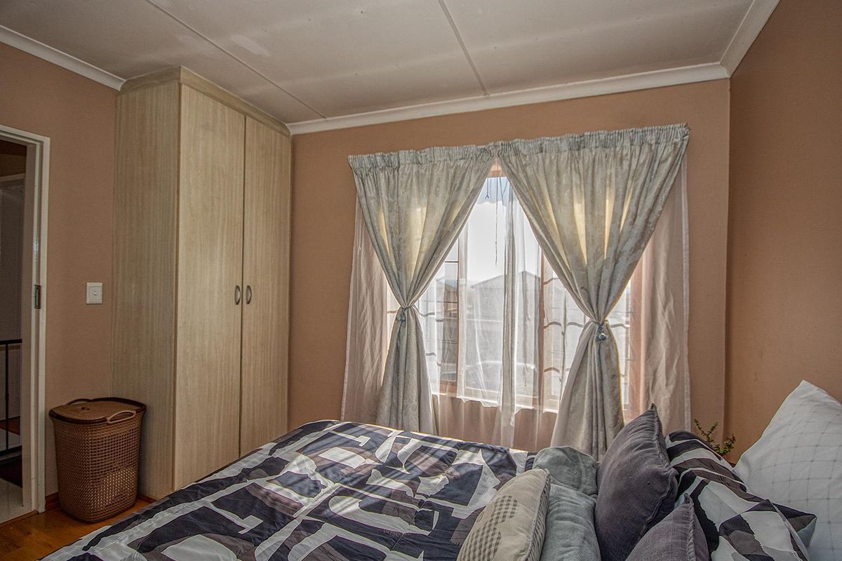 A cozy bedroom featuring built-in wooden cabinetry and a window with natural light, providing a functional and comfortable living space.