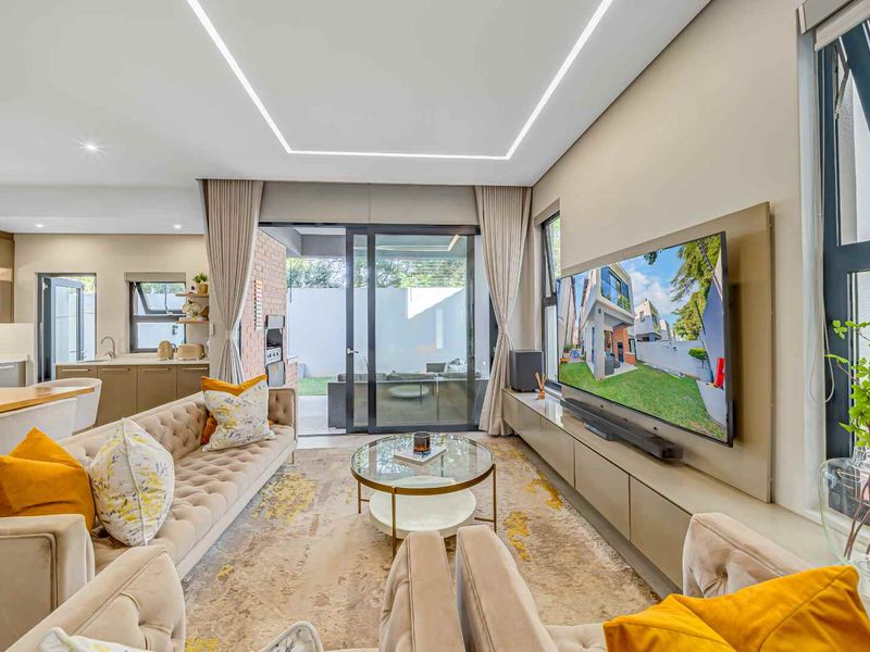 Modern open-plan living area featuring recessed ceiling lighting, sleek built-in cabinetry, and large sliding glass doors that provide seamless access to the outdoor patio.