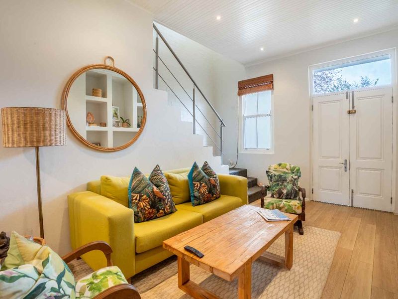 Bright living area featuring timber flooring, a staircase with a modern metal handrail, recessed shelving, and a classic panelled front door.