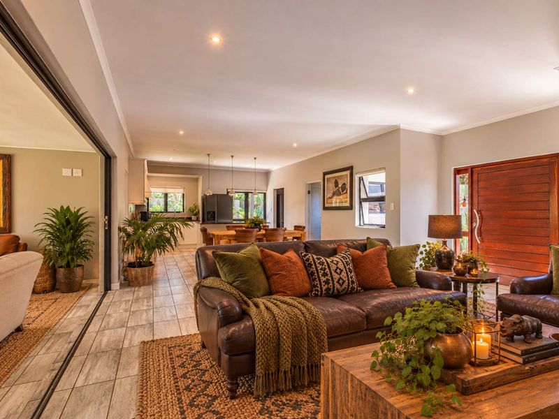 Spacious open-plan living area featuring tiled floors, recessed lighting, and seamless flow to the kitchen and outdoor access through large sliding glass doors.