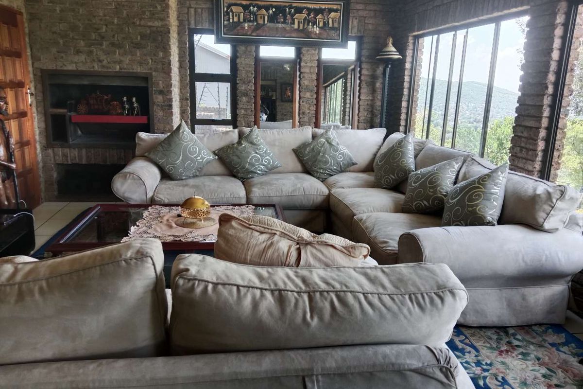Spacious living room featuring exposed brick walls, a built-in fireplace, and large windows offering natural light and scenic views.