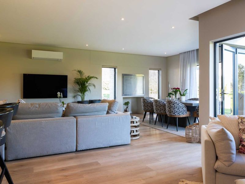 Spacious open-plan living and dining area featuring timber flooring, recessed lighting, a built-in fireplace, and seamless access to the outdoors via bi-fold doors.